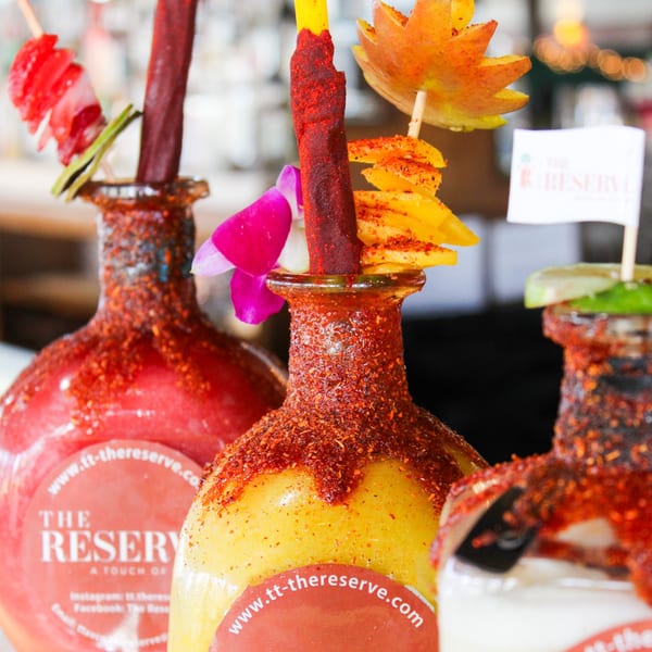 Three colorful Mexican drinks, garnished with fruit, candy, and chili, from The Reserve restaurant.