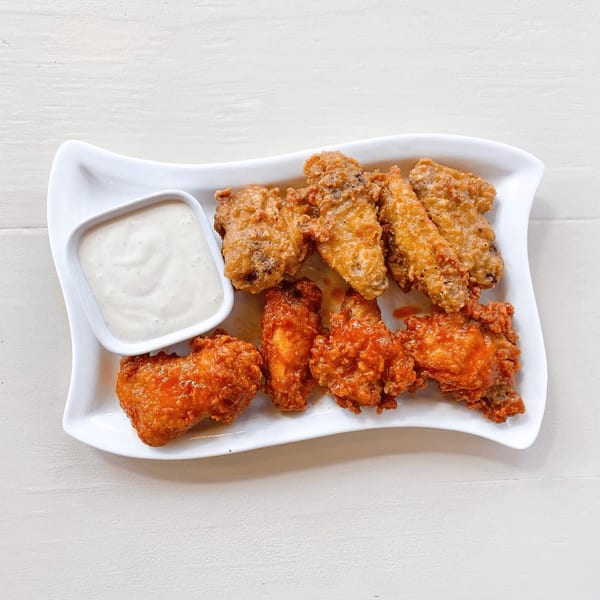 A white plate with two types of chicken wings and a side of ranch dressing.