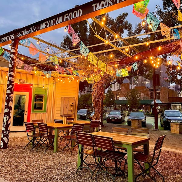Outdoor patio of The Reserve restaurant with string lights, colorful papel picado, and wooden tables.