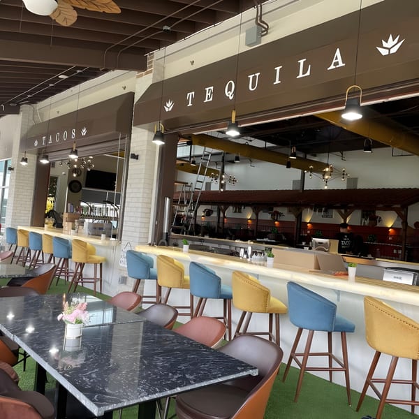 The Reserve's Mexican restaurant interior with a "Tacos" and "Tequila" bar, colorful stools, and marble tables.