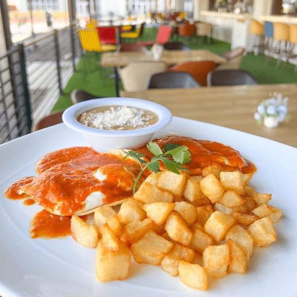 Mexican breakfast with eggs in red sauce, crispy potatoes, and a side of refried beans.