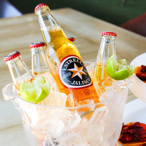 Estrella Jalisco beer bottles with lime wedges in an ice bucket at The Reserve.