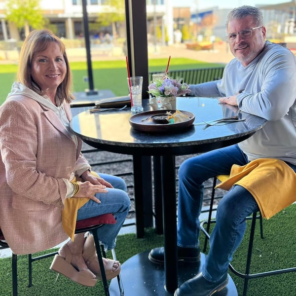 A smiling couple enjoying Mexican food and drinks at an outdoor table at The Reserve.