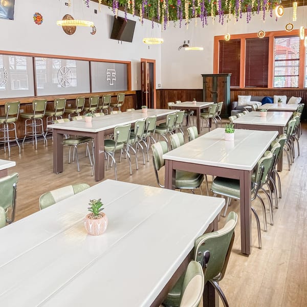 The Reserve restaurant interior with long tables, green chairs, and hanging floral decorations.