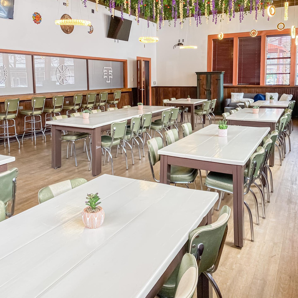 The Reserve restaurant interior with long tables, green chairs, and hanging floral decorations.