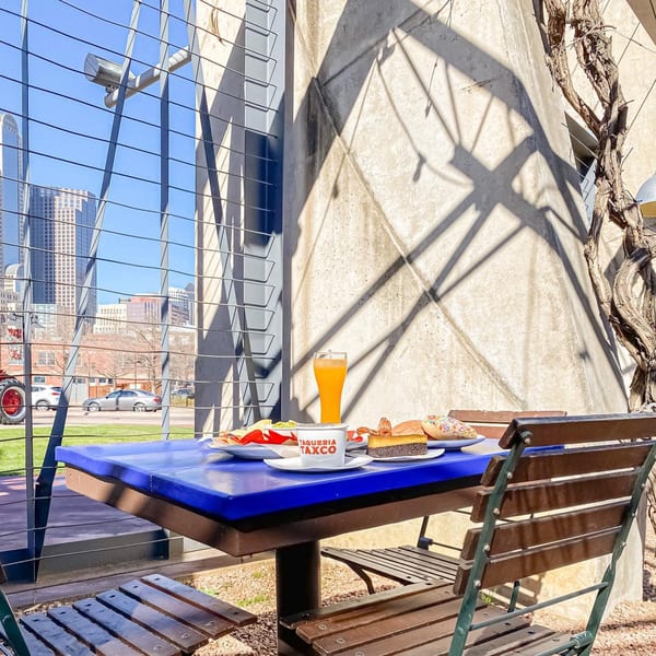 A blue outdoor table at The Reserve with Mexican food, drinks, and city buildings in the background.