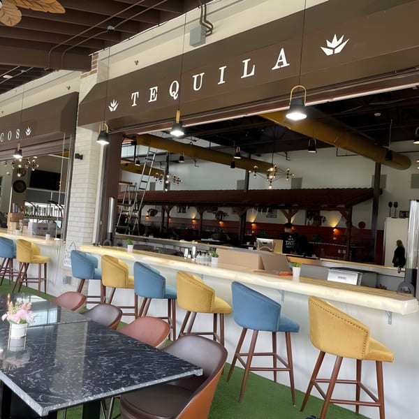 The Reserve's tequila bar with colorful stools, a long marble table, and a brown awning.