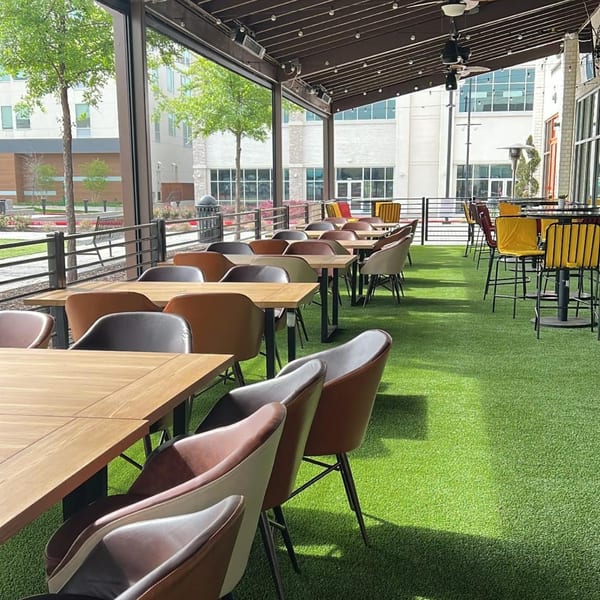 The Reserve's outdoor patio with tables, chairs, and artificial turf, overlooking a city street.
